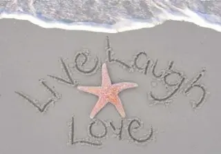 Starfish on sand with "Live Laugh Love" writing