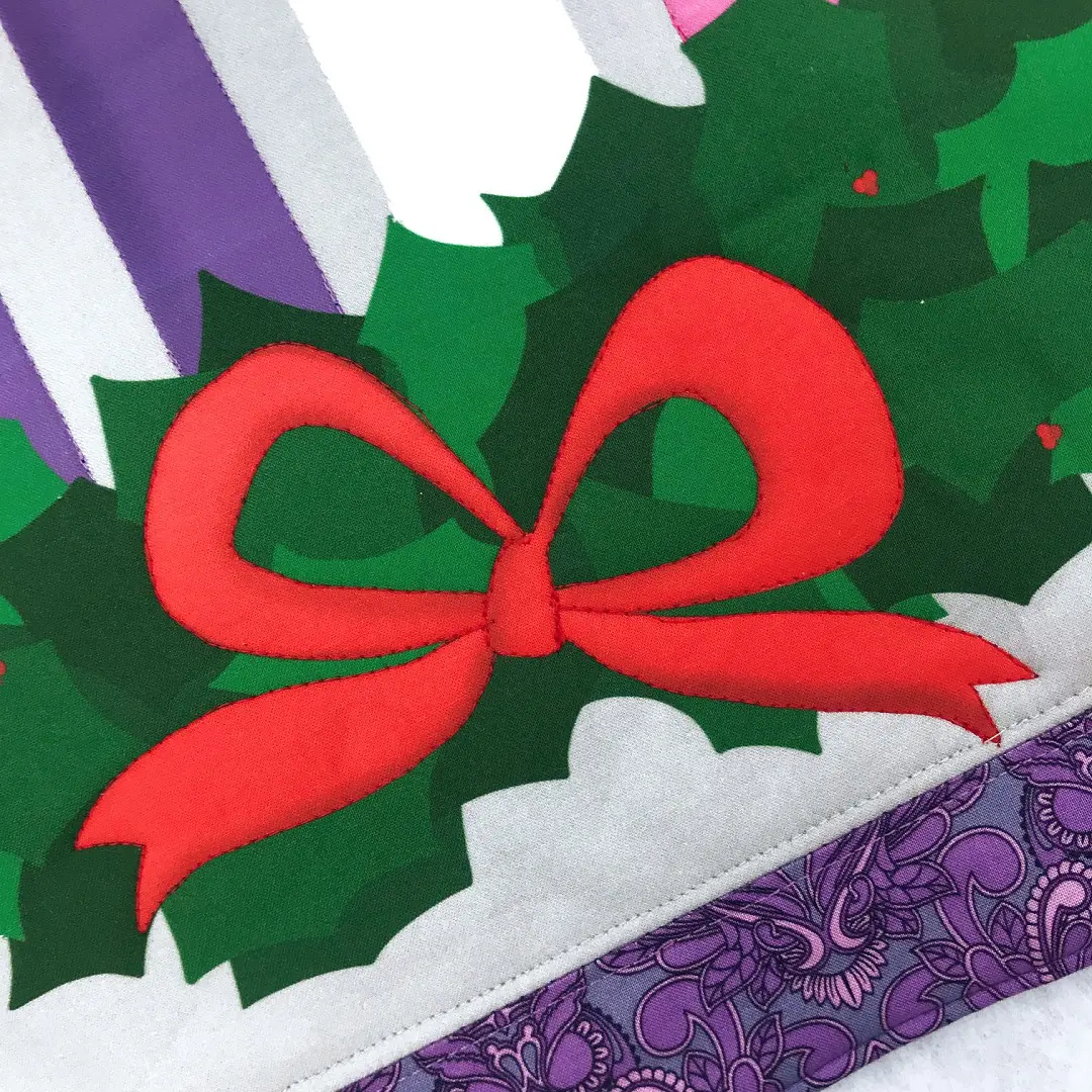 Red bow on holly with purple fabric