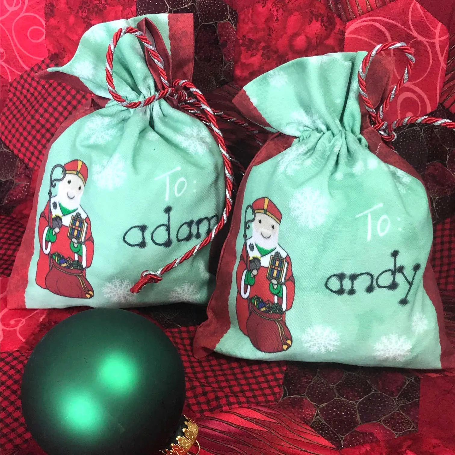 Two green Christmas gift bags with ornament